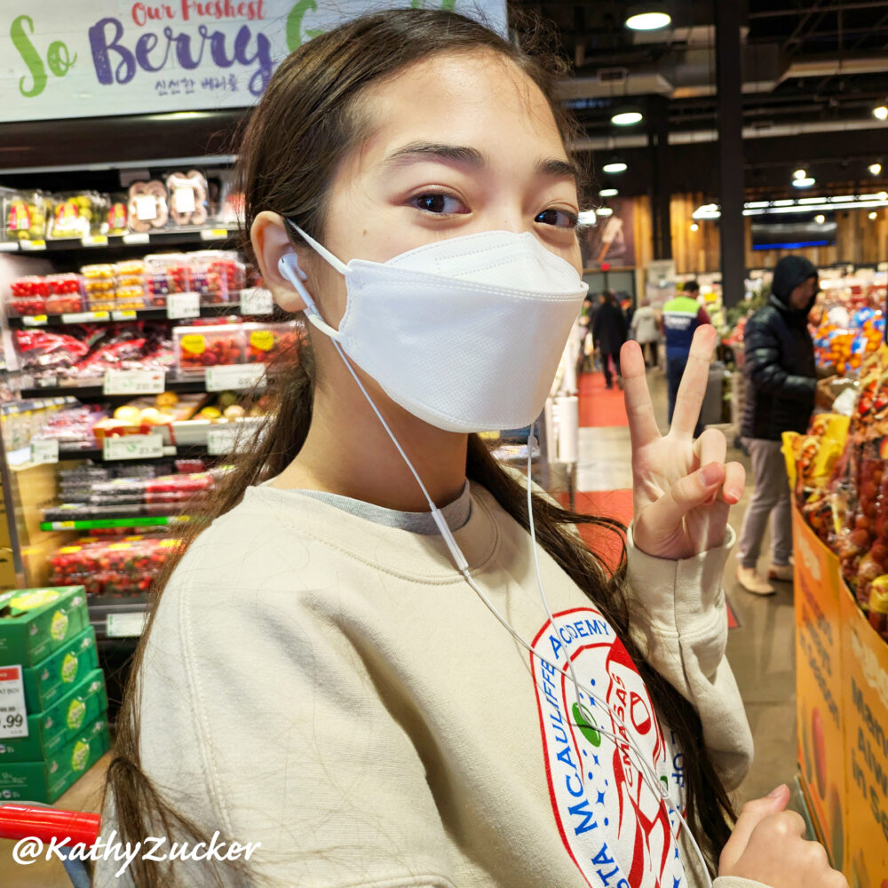 Young girl wearing a medical mask stands in grocery store