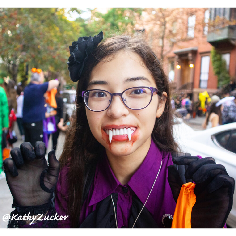 Young girl wearing vampire costume standing on New York City street during Halloween celebration