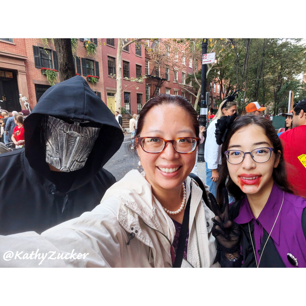 Mother and two children wearing Halloween costumes stand on New York City street